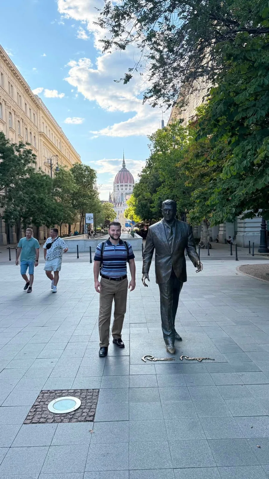 Zachary Tayler beside a statue of Ronald Reagan in Budapest